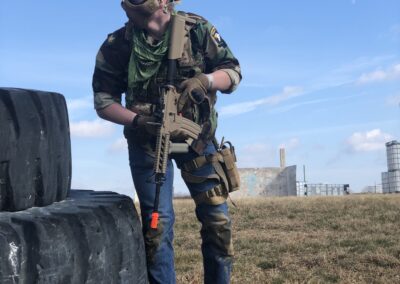 Airsoft player looking over his shoulder while taking cover at Cousins Paintball